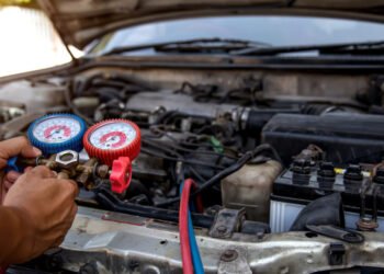 Auto mechanic using measuring equipment tool for filling car air conditioners fix checking. Concepts of Old car Repair service and insurance.